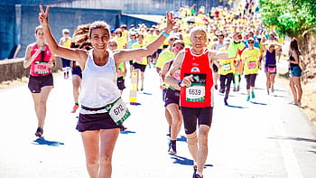 A group of diverse runners participating in a lively marathon event under the sun. HD wallpaper