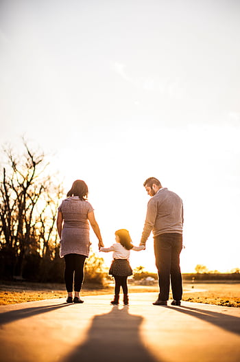 A family of three walks hand in hand at sunset, enjoying togetherness and warmth. HD phone wallpaper