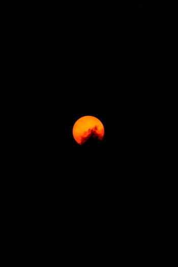 Captivating view of the orange moon setting in the dark night sky, creating a dramatic celestial scene. HD phone wallpaper