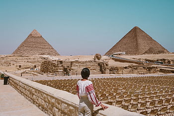A tourist admires the Great Pyramids and Sphinx in Giza, Egypt under the clear daytime sky. HD wallpaper