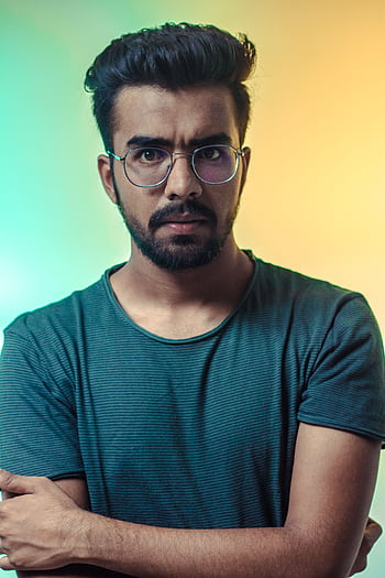 A thoughtful adult man with eyeglasses posing for a portrait with a vibrant backdrop. HD phone wallpaper