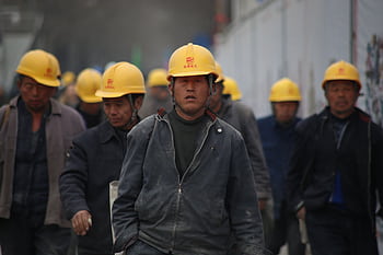 Construction workers in hard hats walking at a site, highlighting teamwork and safety. HD wallpaper