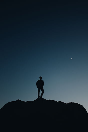Silhouette of a person standing on a hilltop under a crescent moon during dusk. HD phone wallpaper