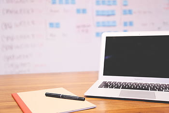 Clean and organized workspace with a laptop, notepad, and pen for planning and projects. HD wallpaper
