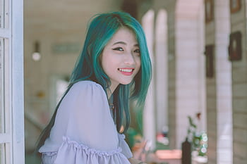 Beautiful young woman with vibrant green hair smiling happily indoors. HD wallpaper