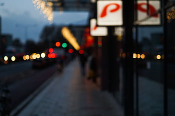 Blurred city street scene at night with bokeh lights and illuminated signs. HD wallpaper