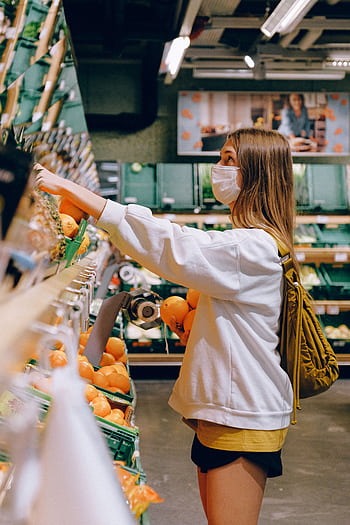 Woman wearing mask choosing oranges in a supermarket during the pandemic. HD phone wallpaper