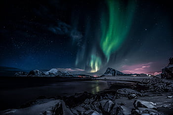 Stunning view of aurora borealis over snow-capped peaks in Nordland, Norway under a starry night sky. HD wallpaper