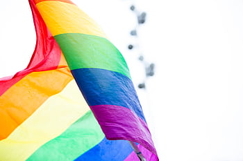 A colorful rainbow pride flag waves against a bright sky, symbolizing LGBTQ+ celebration and diversity. HD wallpaper