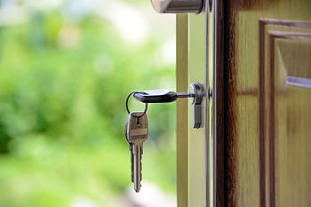 Key inserted in door lock against a blurred green background, symbolizing security and real estate. HD wallpaper