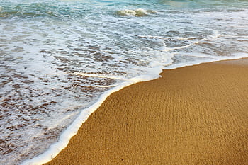 Serene sandy beach with gentle ocean waves perfect for a calming background. HD wallpaper