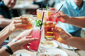 Friends enjoying a toast with vibrant cocktails at an indoor gathering. HD wallpaper