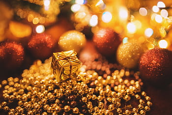 Close-up of golden gift and beads amidst glowing holiday decorations, creating a warm festive ambiance. HD wallpaper