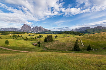 Breathtaking view of Alpe di Siusi in Italy, featuring lush green fields and towering Dolomites under a vivid sky. HD wallpaper