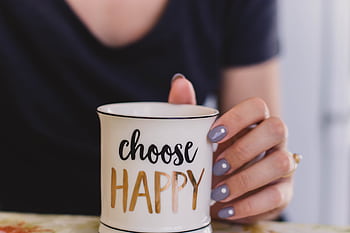 A woman holds a mug with 'choose happy' text indoors, promoting positivity. HD wallpaper