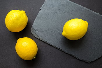 High-angle shot of vibrant lemons on dark slate, emphasizing freshness. HD wallpaper
