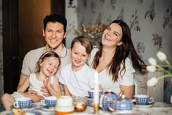 Cheerful family of four enjoying a warm and cozy teatime at home, surrounded by love and laughter. HD wallpaper