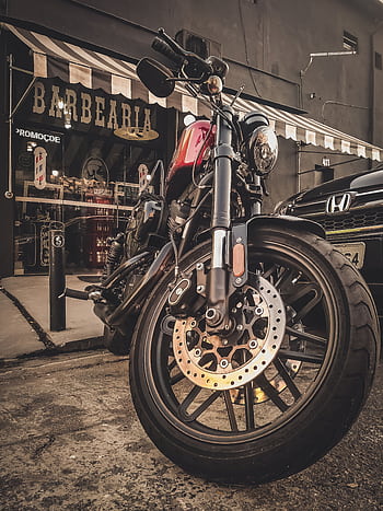 A stylish vintage motorcycle parked outside a classic barbershop with a rustic ambiance. HD phone wallpaper