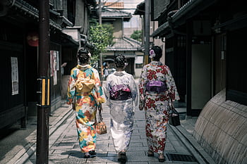 Three women in colorful kimonos walking through a traditional street in Kyoto, Japan. HD wallpaper