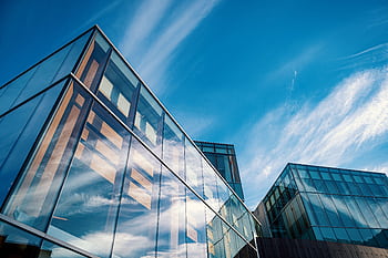 Low angle view of contemporary glass office buildings reflecting a vibrant blue sky. HD wallpaper