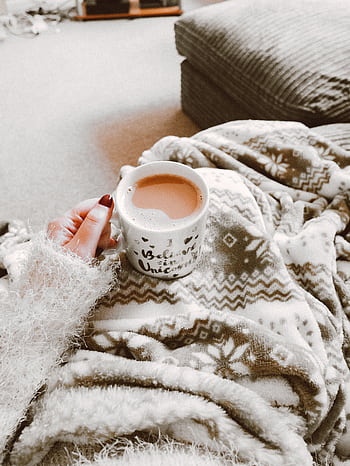 Person holding a hot drink surrounded by cozy blanket indoors. Perfect for winter comfort. HD phone wallpaper