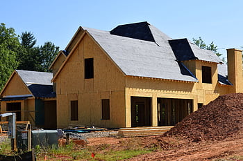 A partially built wooden house under construction, showcasing its progress and design in daylight. HD wallpaper