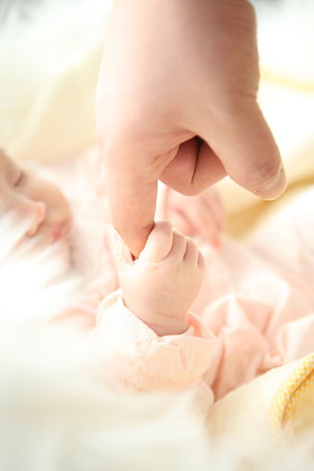 Heartwarming close-up of a baby holding a parent's finger, symbolizing love and connection. HD phone wallpaper