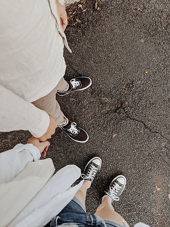 Top view of a couple casually holding hands on a paved road, showcasing casual fashion and intimacy. HD phone wallpaper