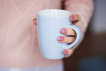A woman's hand with pink nails holding a light blue mug, indoors. HD wallpaper