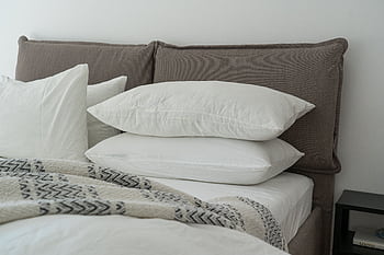 Modern bedroom featuring clean white bedding and pillows for a cozy and inviting atmosphere. HD wallpaper