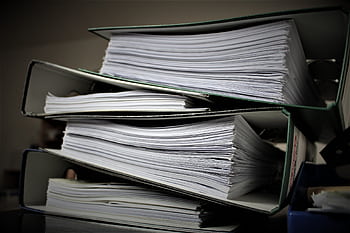 Close-up of stacked binders filled with documents for office or educational use. HD wallpaper