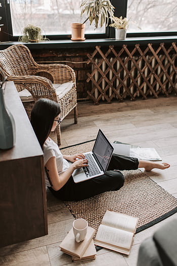 A young woman in casual attire working from home using a laptop while sitting on the floor with a coffee mug nearby. HD phone wallpaper