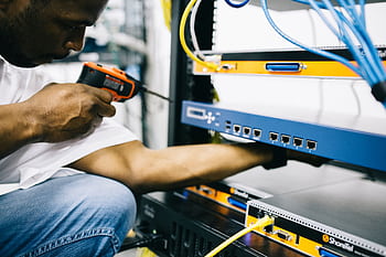 Technician concentrating on equipment maintenance and repair in data center with precision. HD wallpaper