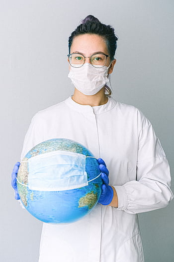 Conceptual of a doctor holding a globe with a mask, symbolizing global health. HD phone wallpaper