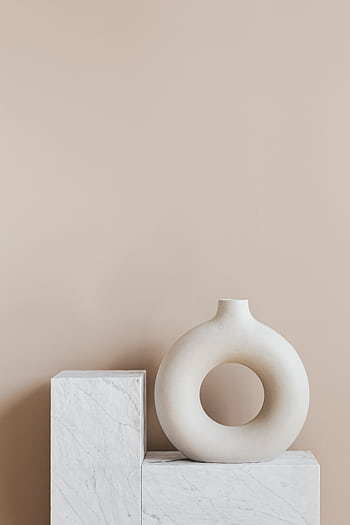 Elegant white ceramic vase with circular design on marble stand in minimalist setting. HD phone wallpaper