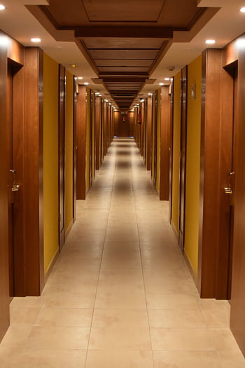 Long hallway view of a modern hotel with wooden doors and ceiling, creating a luxurious ambiance. HD phone wallpaper