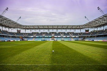 Explore a soccer stadium with clear skies and pristine grass, perfect for any sports event. HD wallpaper