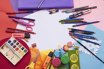 A vibrant selection of school supplies on a desk, including paints and stationery, ideal for creative projects. HD wallpaper
