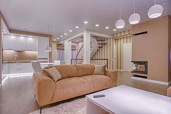 Luxurious living room with modern interior design, featuring beige sofa, fireplace, and open kitchen. HD wallpaper