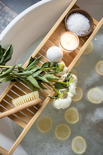 A serene spa setting with lemon slices, flowers, and calming essentials in a bathtub. HD phone wallpaper