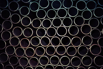 A detailed macro shot of stacked metal tubes forming a circular pattern, highlighting industrial design. HD wallpaper