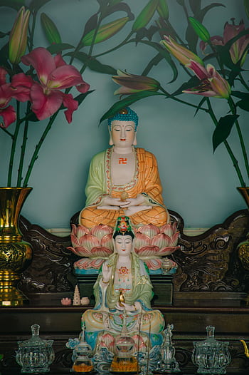 Intricate Buddhist altar with colorful statues and pink lilies for worship HD phone wallpaper