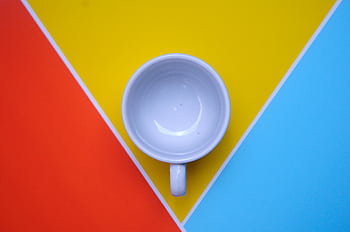 Overhead shot of a white mug on vibrant red, yellow, and blue background. Perfect for design and modern themes. HD wallpaper