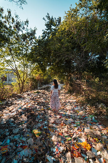 A woman walks through a forested area littered with plastic waste in Myanmar. HD phone wallpaper