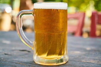 A refreshing cold beer in a clear glass mug set outdoors on a sunny day. HD wallpaper