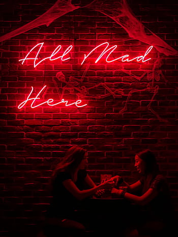 Two women enjoying a night out under a red neon sign with a playful phrase. HD phone wallpaper