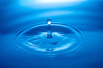 Capture of a water droplet creating ripples on a blue surface showcasing tranquility and clarity. HD wallpaper