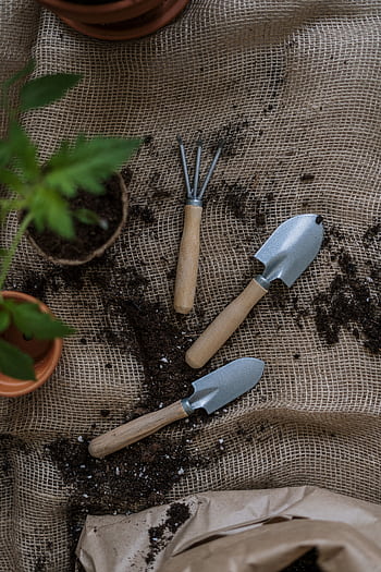 Gardening tools with potted plants and soil on burlap, perfect for home gardening themes. HD phone wallpaper