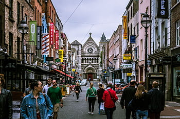 A bustling street scene in Dublin, showcasing diverse people and historic architecture. HD wallpaper
