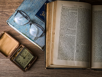 A vintage setting with antique books, watch, and reading glasses on a wooden table. HD wallpaper